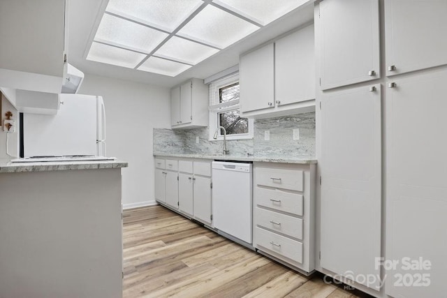 kitchen featuring a sink, white appliances, light wood-style floors, light countertops, and decorative backsplash