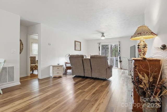 living area with baseboards, a ceiling fan, visible vents, and light wood-type flooring