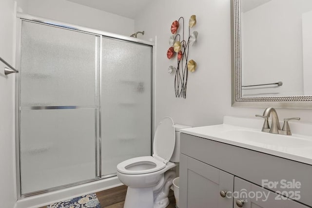 full bath with a stall shower, toilet, vanity, and wood finished floors