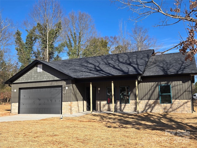 view of front of house featuring a garage, stone siding, roof with shingles, and concrete driveway