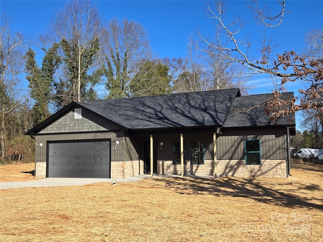 view of front of home with an attached garage, stone siding, driveway, and roof with shingles