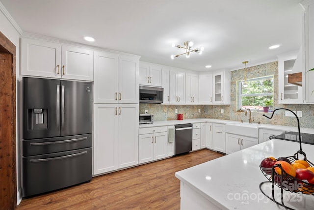 kitchen featuring stainless steel appliances, white cabinetry, light countertops, tasteful backsplash, and glass insert cabinets