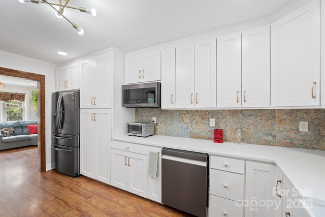 kitchen with white cabinets, light wood-style flooring, stainless steel appliances, light countertops, and backsplash