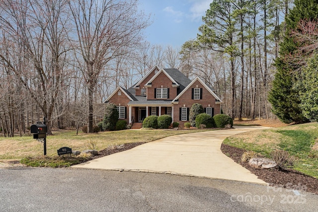 view of front of property with driveway, a front yard, and brick siding