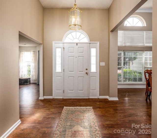 entrance foyer with a chandelier, wood finished floors, and baseboards