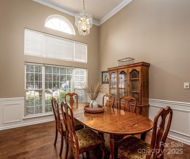 dining space featuring ornamental molding, wood finished floors, a notable chandelier, and wainscoting