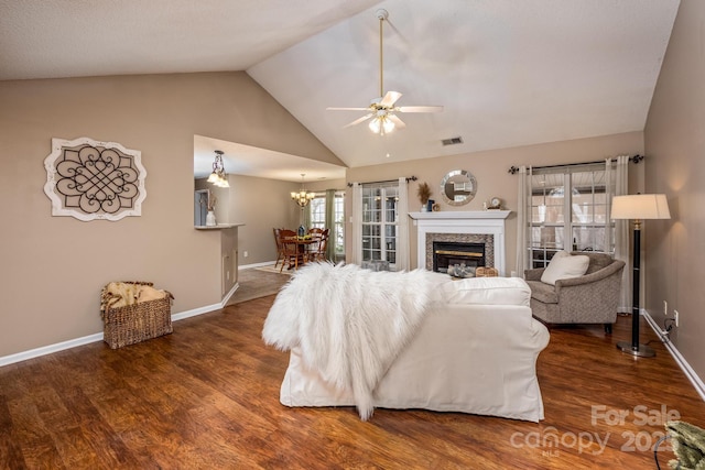 living room with visible vents, a glass covered fireplace, vaulted ceiling, wood finished floors, and ceiling fan with notable chandelier