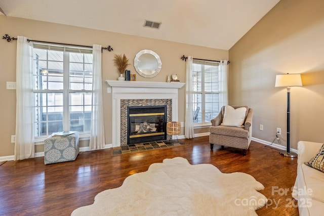 sitting room with a fireplace, lofted ceiling, visible vents, wood finished floors, and baseboards