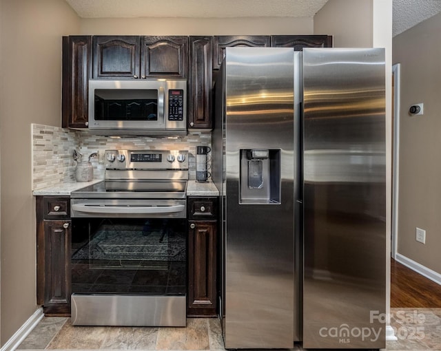 kitchen featuring dark brown cabinetry, tasteful backsplash, appliances with stainless steel finishes, and a textured ceiling