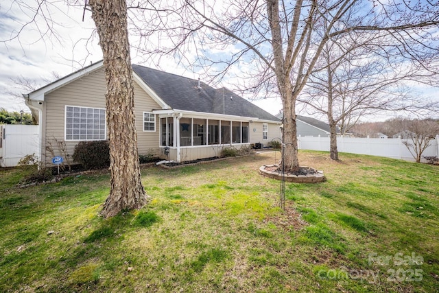 back of property with a sunroom, roof with shingles, a yard, and fence