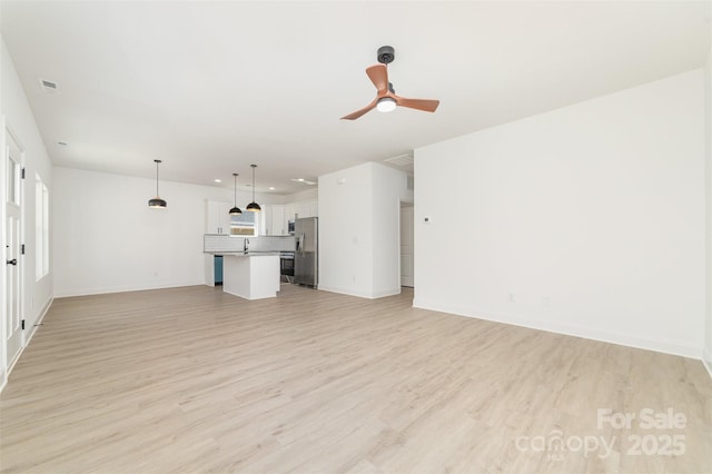 unfurnished living room with baseboards, visible vents, light wood-style flooring, and a ceiling fan