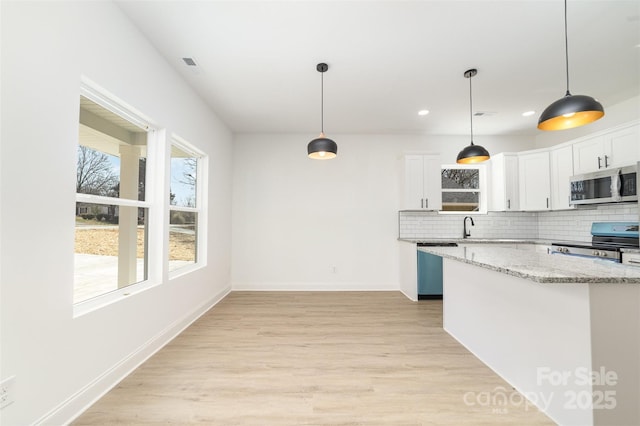 kitchen featuring light wood-style flooring, stainless steel appliances, white cabinetry, light stone countertops, and tasteful backsplash