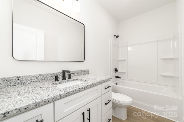 bathroom with toilet, shower / bathing tub combination, wood finished floors, and vanity