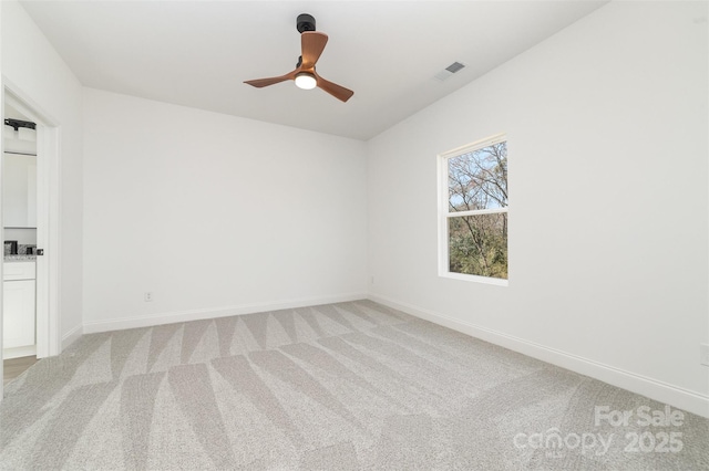 spare room featuring baseboards, ceiling fan, visible vents, and light colored carpet