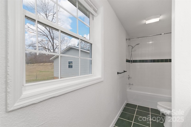 full bath featuring tile patterned floors, baseboards, toilet, and washtub / shower combination