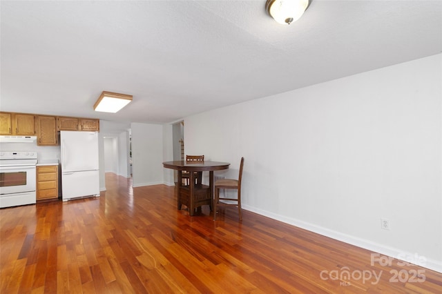 kitchen featuring white appliances, ventilation hood, wood finished floors, and light countertops