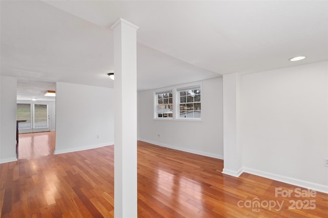 interior space featuring ornate columns, baseboards, and hardwood / wood-style flooring