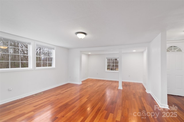 basement featuring visible vents, baseboards, and hardwood / wood-style flooring