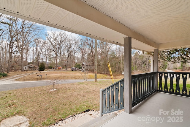 wooden terrace featuring a yard and covered porch