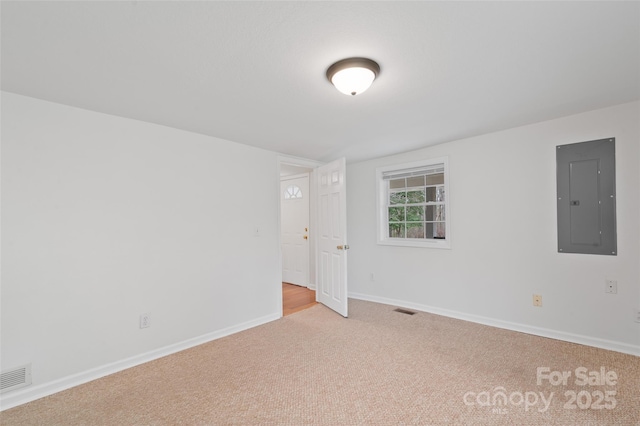 unfurnished room with electric panel, visible vents, baseboards, and light carpet