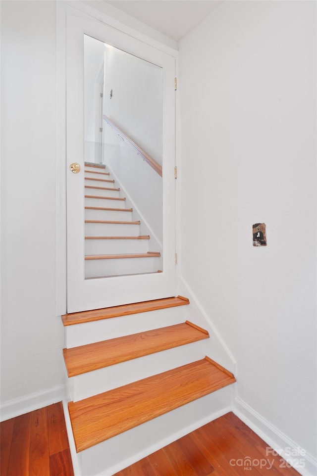 staircase featuring baseboards and wood finished floors