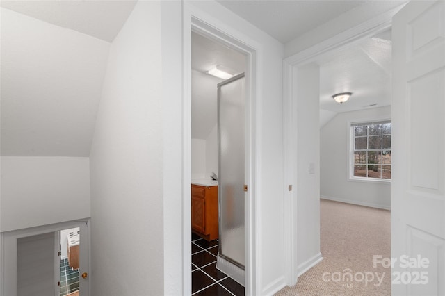 corridor featuring lofted ceiling, light colored carpet, baseboards, and a sink