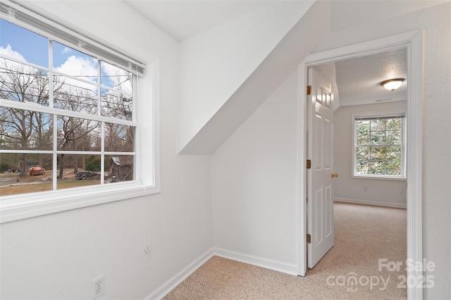 interior space with a textured ceiling, baseboards, and light carpet