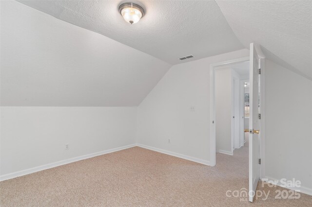 bonus room featuring light carpet, baseboards, visible vents, and a textured ceiling