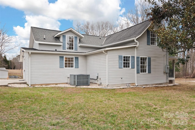 back of house with central air condition unit, a lawn, and roof with shingles