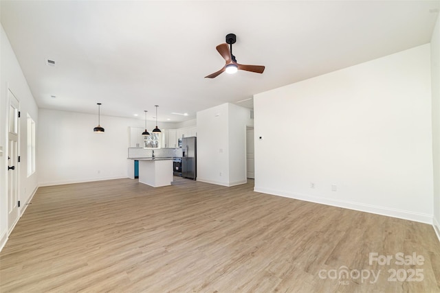 unfurnished living room featuring ceiling fan, light wood finished floors, visible vents, and baseboards