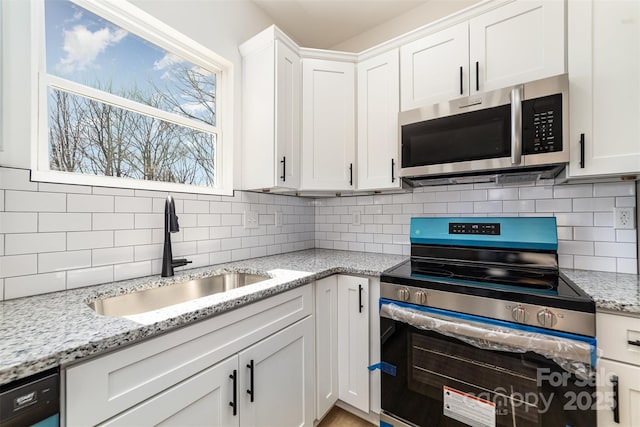 kitchen with stainless steel appliances, white cabinets, a sink, and decorative backsplash