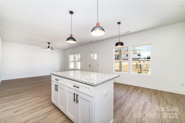 kitchen with open floor plan, light wood-type flooring, a center island, and pendant lighting