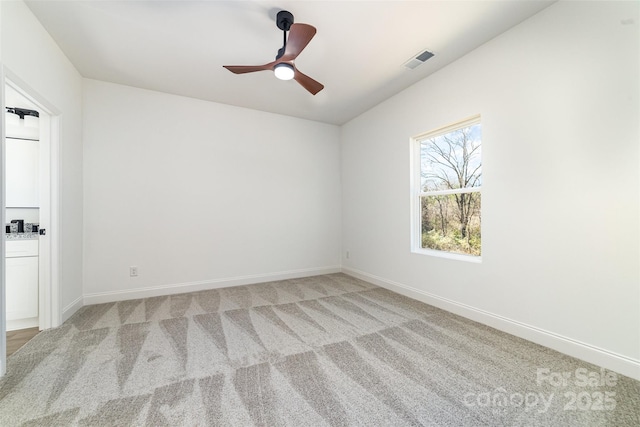 empty room with visible vents, ceiling fan, light carpet, and baseboards