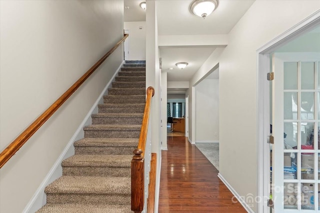 stairway with wood finished floors and baseboards