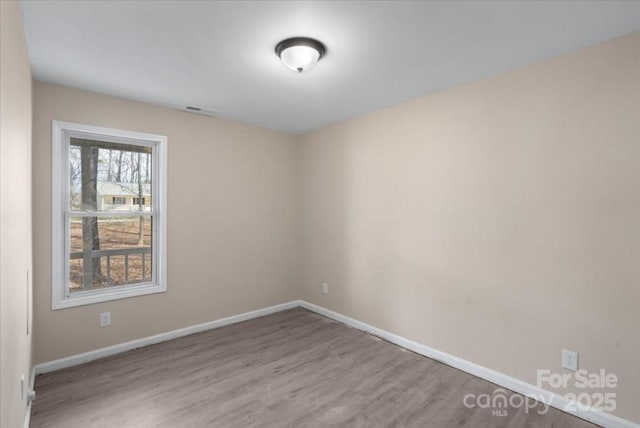 spare room with visible vents, baseboards, and wood finished floors