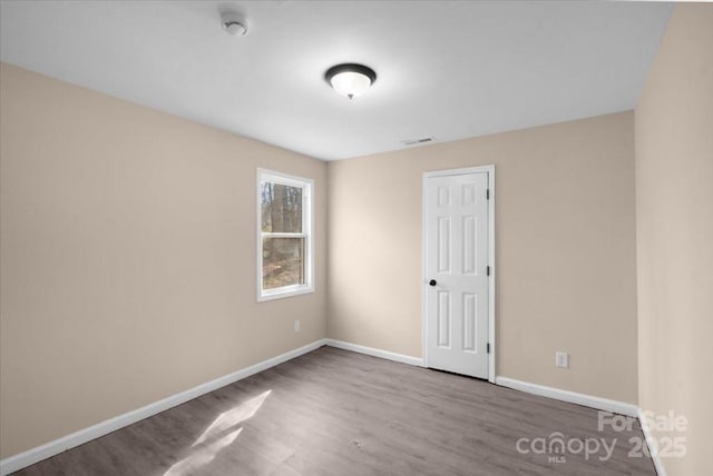 spare room featuring baseboards, visible vents, and wood finished floors