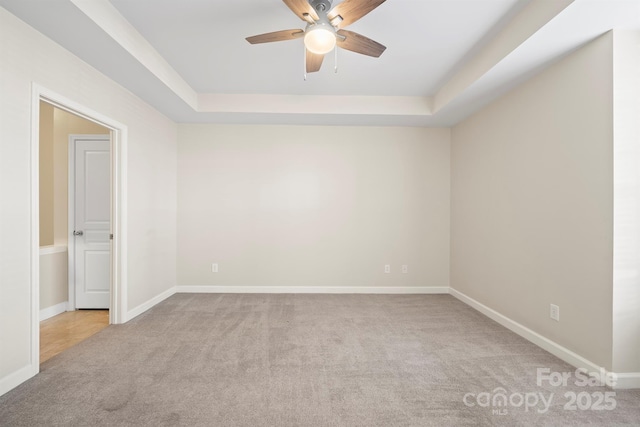 spare room with carpet floors, baseboards, and a raised ceiling