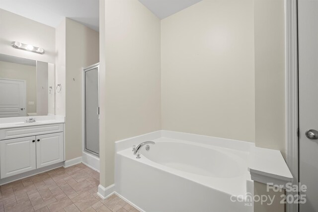 bathroom with a shower stall, baseboards, a bath, and vanity