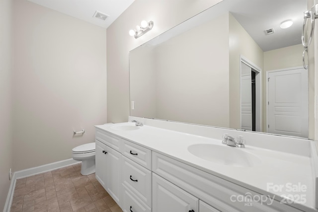 bathroom with toilet, double vanity, a sink, and visible vents