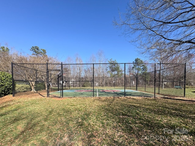 view of tennis court featuring a yard and fence