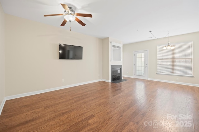 unfurnished living room featuring a fireplace with flush hearth, ceiling fan with notable chandelier, baseboards, and wood finished floors