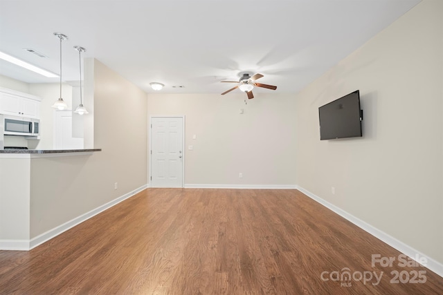 unfurnished living room featuring ceiling fan, wood finished floors, visible vents, and baseboards