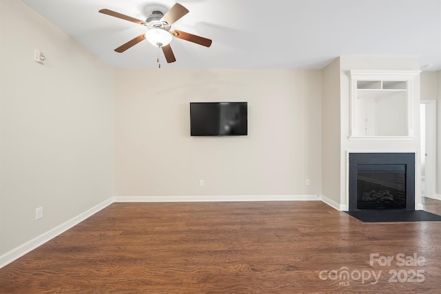 unfurnished living room with dark wood-style floors, a fireplace with flush hearth, baseboards, and a ceiling fan