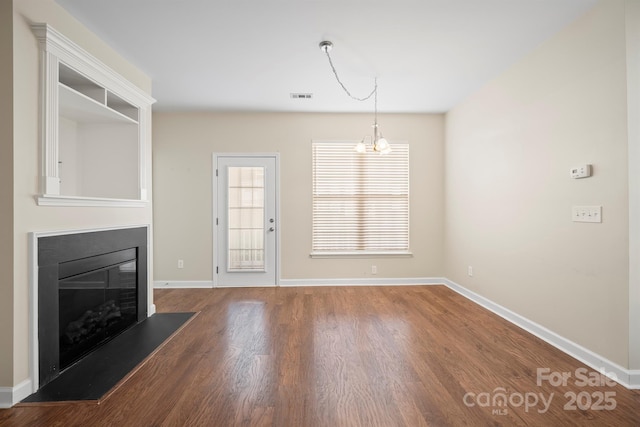 unfurnished living room featuring baseboards, visible vents, wood finished floors, and a glass covered fireplace