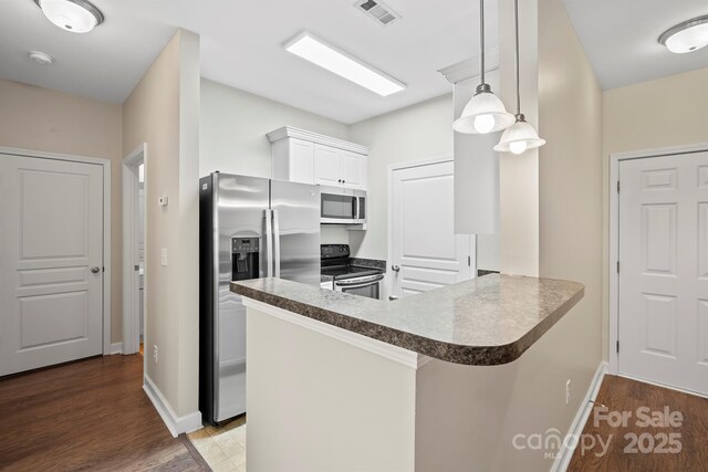 kitchen with stainless steel appliances, a peninsula, wood finished floors, and visible vents