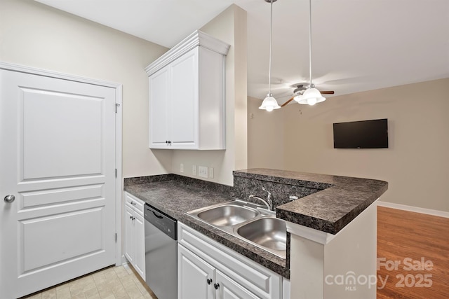 kitchen with dark countertops, a sink, white cabinetry, and stainless steel dishwasher