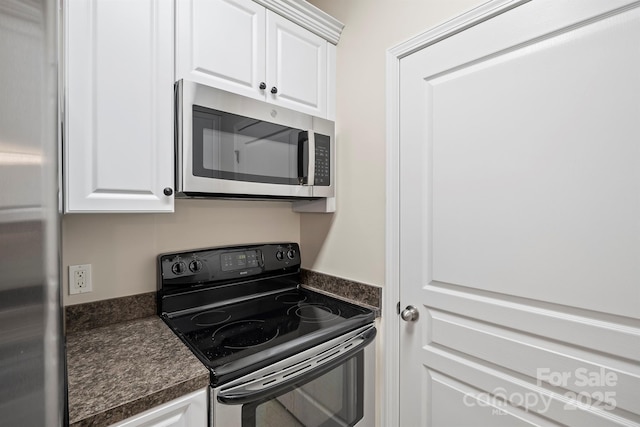 kitchen featuring stainless steel appliances, dark countertops, and white cabinetry