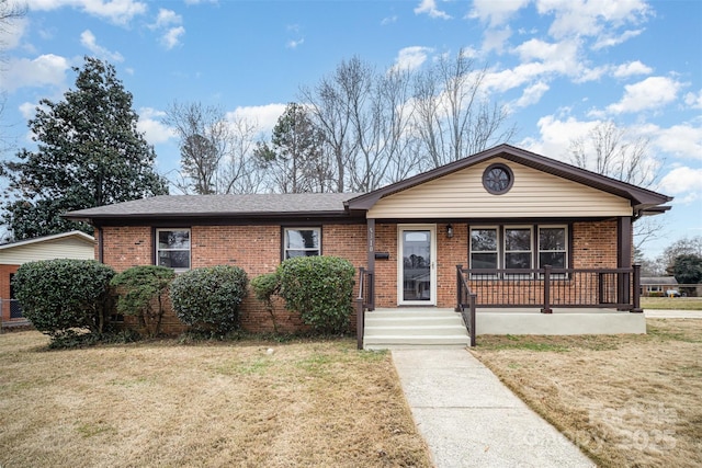 view of front facade featuring a porch, a front yard, brick siding, and roof with shingles