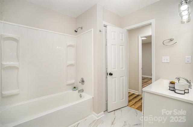 bathroom with marble finish floor, shower / bathing tub combination, vanity, and baseboards