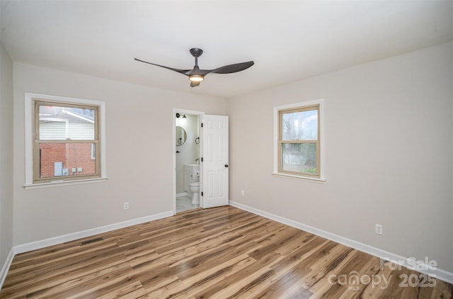 unfurnished room featuring light wood-style floors, a healthy amount of sunlight, visible vents, and baseboards